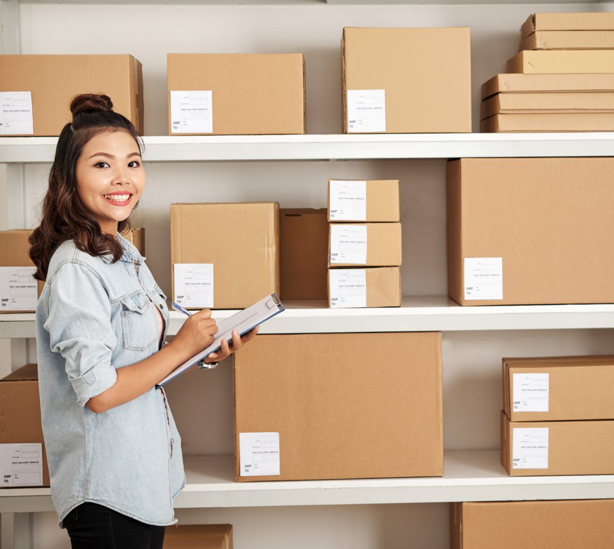 mulher asiatica sorrindo, fazendo anotações de controle de estoque